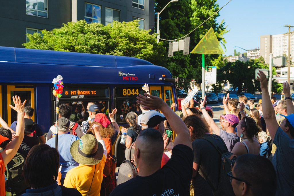 A crowd of bus racers wave at the bus as it finally arrives at the finish line. Image credit: Jared Shute